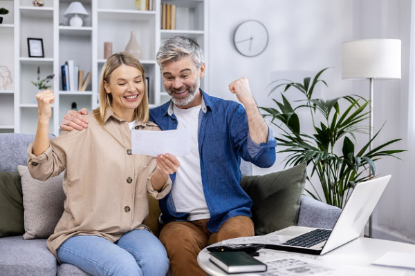 A wife and husband looking happily at a home utility bill.