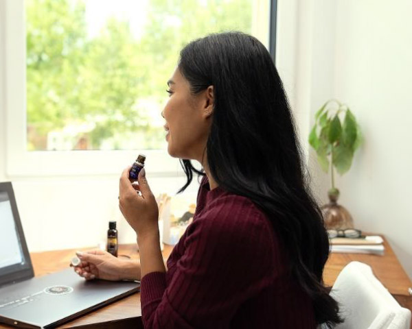 A woman holding a small bottle of essential oil.