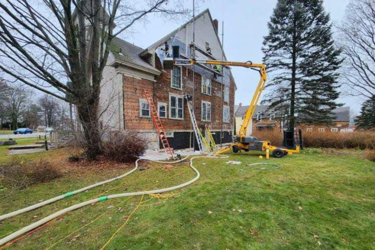 A man using a crane to work on a house, demonstrating construction and engineering skills.